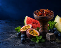 Hookah bowl packed with shisha tobacco surrounded by fresh fruit and mint